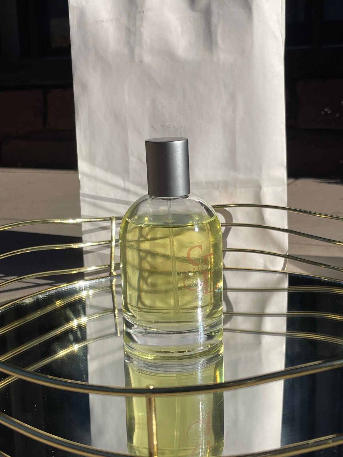 A Scents Eleven Eau de Parfum bottle on a mirrored gold tray